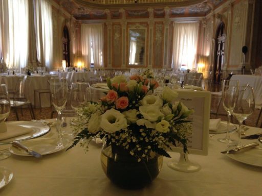 Centro di un elegante ristorante con tavoli apparecchiati e un centro tavola floreale.