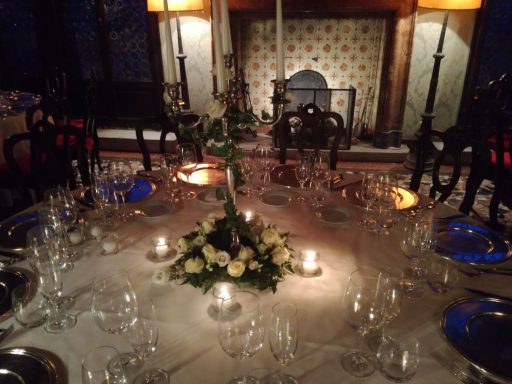 Elegantly set dining table with candles, floral centerpiece, and glassware.