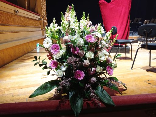 Colorful floral arrangement with pink and white flowers placed on a wooden stage.