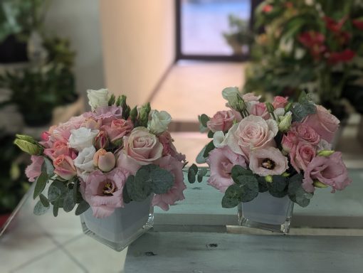 Bouquets of pink and white flowers in decorative containers.