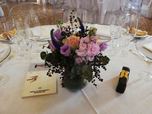 Bouquet of mixed flowers in a glass vase on a dining table.