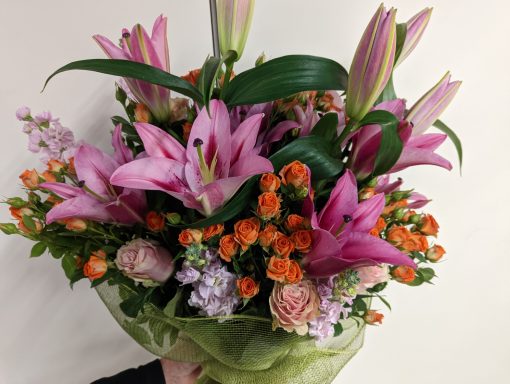 Bouquet of pink lilies, orange and purple flowers, arranged elegantly.