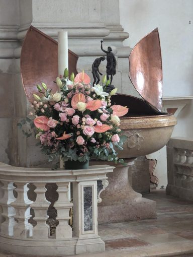Florero di fiori colorati in una chiesa accanto a una fontana battesimale.