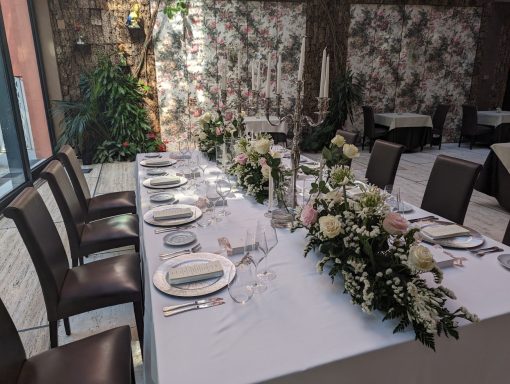 Elegantly set dining table with floral centerpieces in a decorated venue.