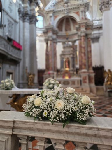 Bouquet of white flowers in a church, with ornate decorations in the background.
