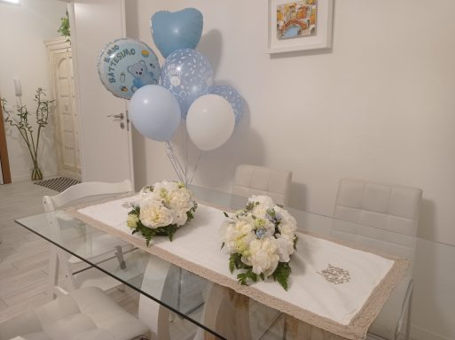 Decorative table with blue and white balloons and floral centerpieces.
